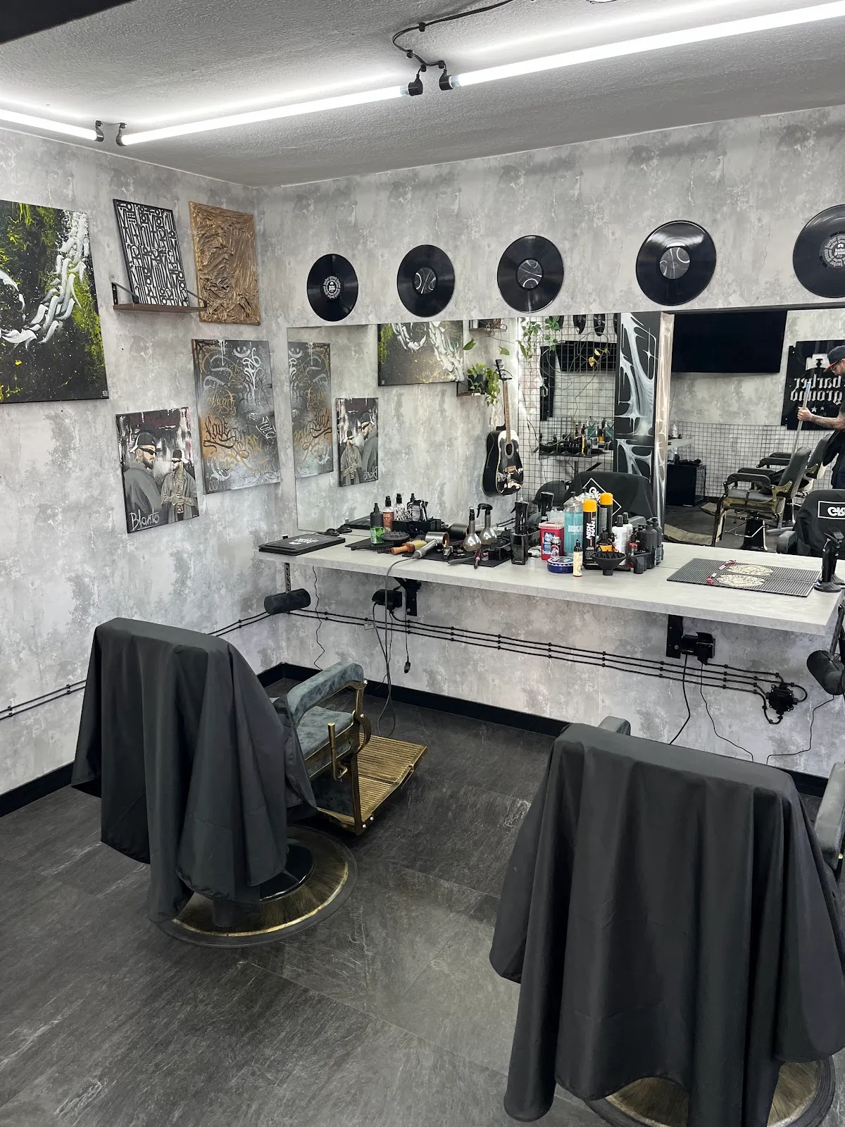 Stanowiska barberskie w Barberground z winylami na ścianie, kosmetykami i fotelami